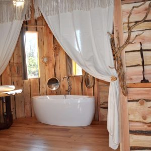 Hébergement insolite en bois avec baignoire élégante et décor naturel chaleureux.