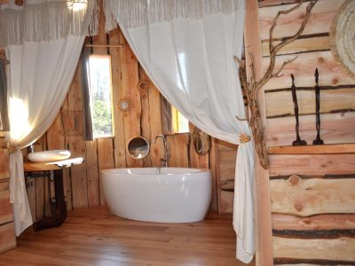 Hébergement insolite en bois avec baignoire élégante et décor naturel chaleureux.