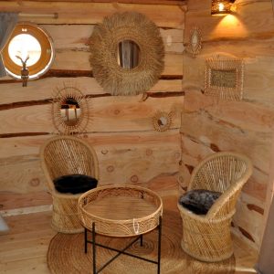 Hébergement insolite en bois avec chaises en osier et décor naturel chaleureux.