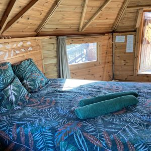 Cabane en bois avec lit douillet et décoration tropicale dans le Pays de la Loire.