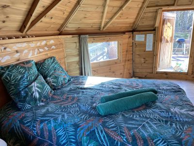 Cabane en bois avec lit douillet et décoration tropicale dans le Pays de la Loire.
