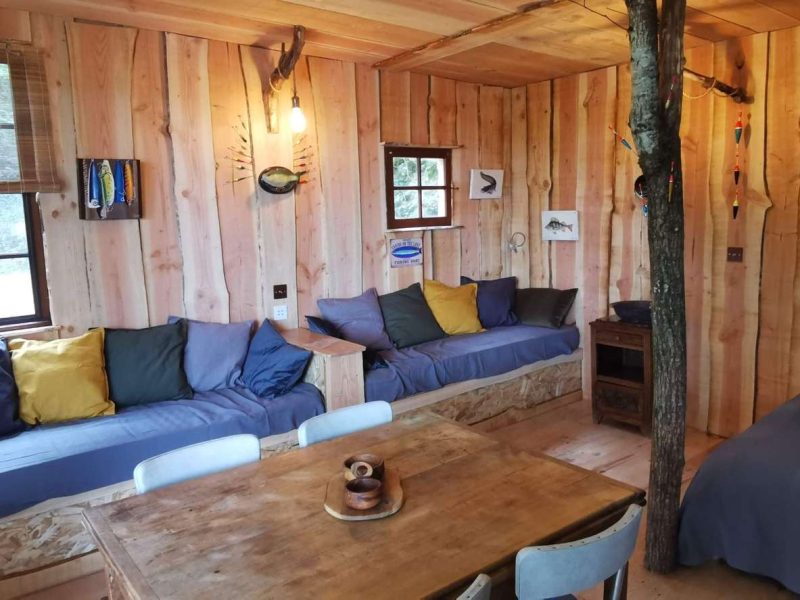 Cabane en bois chaleureuse avec canapés colorés et table en bois.