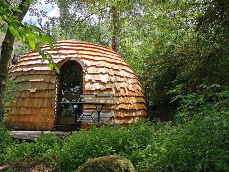 Cabane en bois au toit en ardoise, nichée dans la verdure de Nouvelle-Aquitaine.