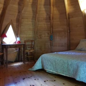 Hébergement insolite en Nouvelle-Aquitaine : cabane en bois avec lit douillet et lumière naturelle.