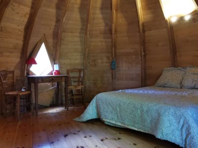Hébergement insolite en Nouvelle-Aquitaine : cabane en bois avec lit douillet et lumière naturelle.