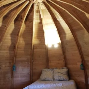 Cabane en bois avec un plafond en bois sculpté et un lit douillet.