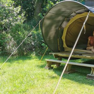 Tente ronde en pleine nature, avec une terrasse en bois et un coin salon.