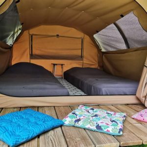Tente safari spacieuse en Nouvelle-Aquitaine, avec lits confortables et coussins colorés.