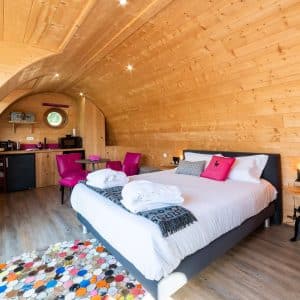 Hébergement insolite en Bourgogne : chambre en bois avec lit douillet et décor coloré.
