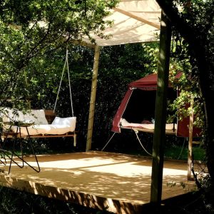 Hébergement insolite en Midi-Pyrénées : plateforme suspendue avec hamac et tente rouge.