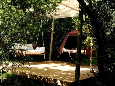 Hébergement insolite en Midi-Pyrénées : plateforme suspendue avec hamac et tente rouge.