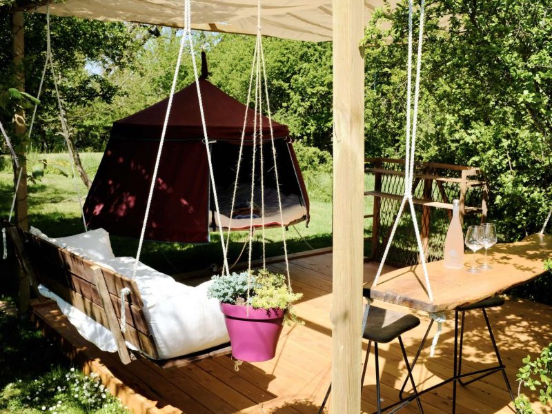 Hébergement insolite en Midi-Pyrénées : tente suspendue avec terrasse en bois et plantes.