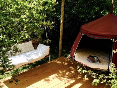 Hébergement insolite en Midi-Pyrénées : tente suspendue avec un coin détente en bois.