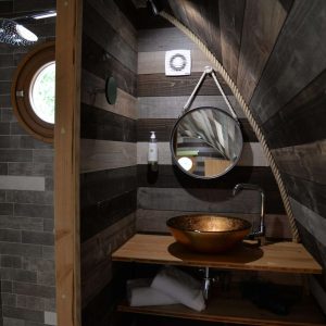Hébergement insolite en Bourgogne : salle de bain avec lavabo en cuivre et murs en bois.