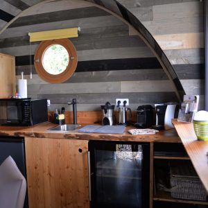 Hébergement insolite en Bourgogne : intérieur en bois avec cuisine moderne et fenêtre ronde.