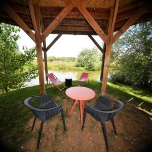 Hébergement insolite en Bourgogne : cabane avec vue sur le lac et mobilier extérieur.