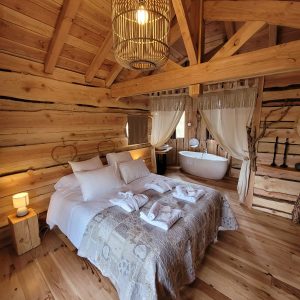 Chalet en bois chaleureux avec lit douillet et baignoire sur pied. Ambiance cocooning.