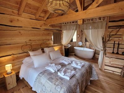 Chalet en bois chaleureux avec lit douillet et baignoire sur pied. Ambiance cocooning.
