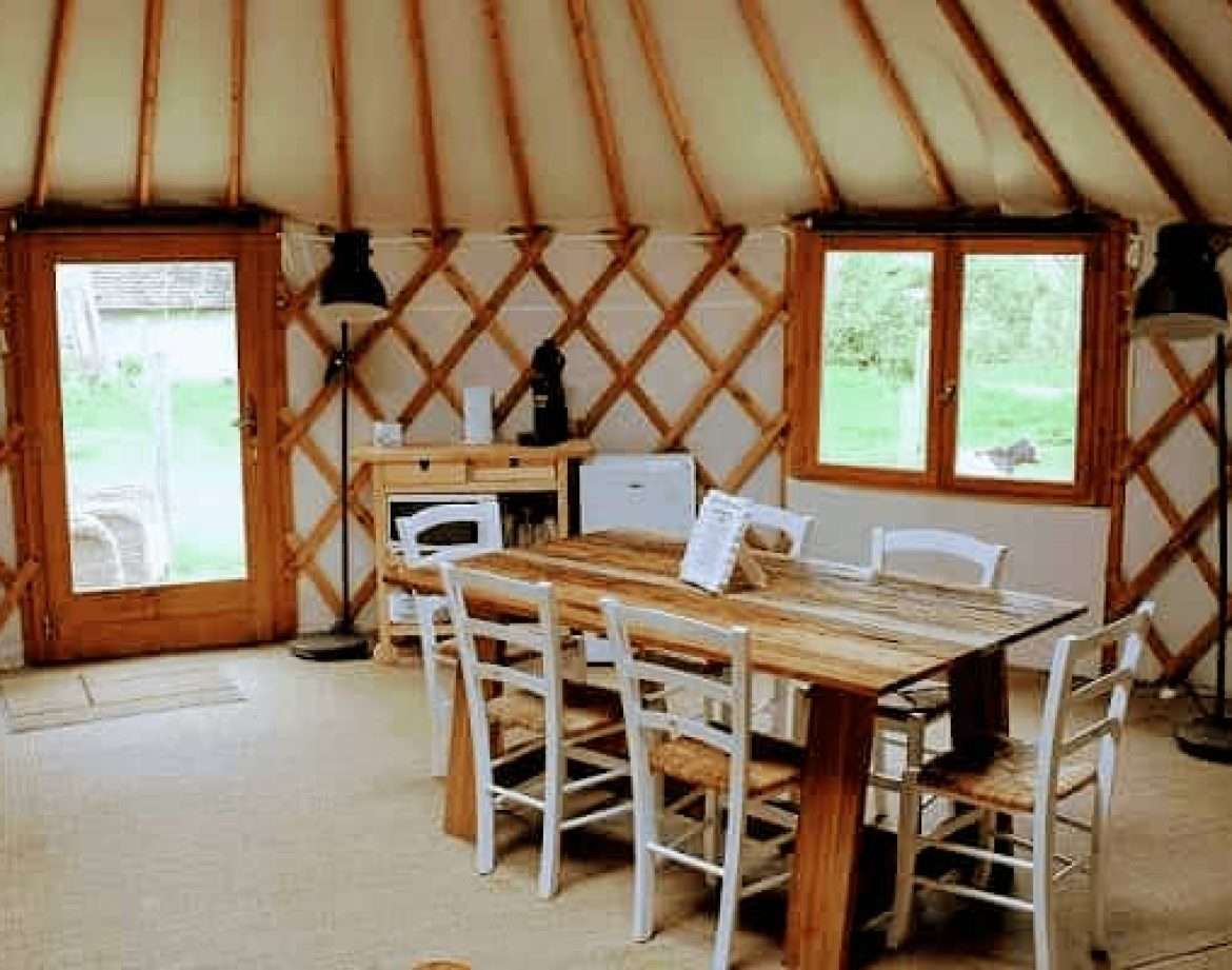 Yourte spacieuse avec un intérieur en bois chaleureux et une grande table à manger.