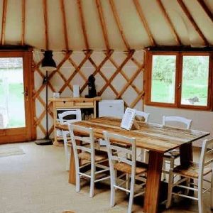 Yourte spacieuse avec un intérieur en bois chaleureux et une grande table à manger.