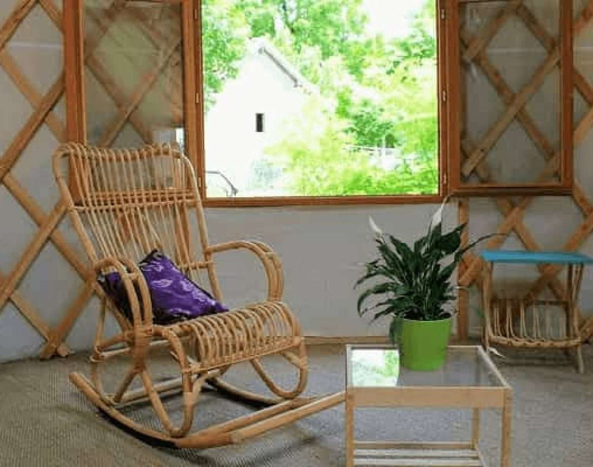 Yourte cosy au Centre, avec fauteuil en rotin et vue sur la nature verdoyante.