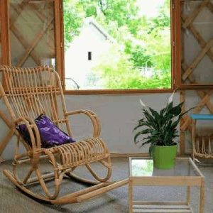 Yourte cosy au Centre, avec fauteuil en rotin et vue sur la nature verdoyante.