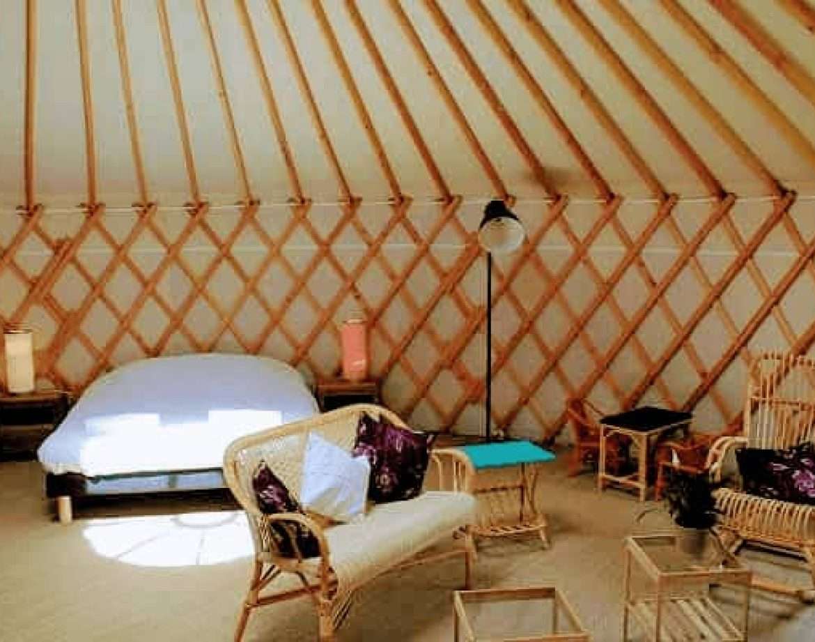 Yourte spacieuse au Centre, avec lit douillet et mobilier en rotin chaleureux.
