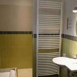 Salle de bain moderne dun hébergement insolite avec carrelage vert et miroir décoratif.