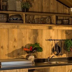 Hébergement insolite en bois avec cuisine équipée et étagères décoratives.