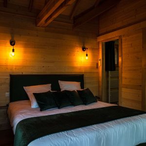 Chalet en bois chaleureux avec lit douillet et éclairage tamisé. Parfait pour un séjour relaxant.