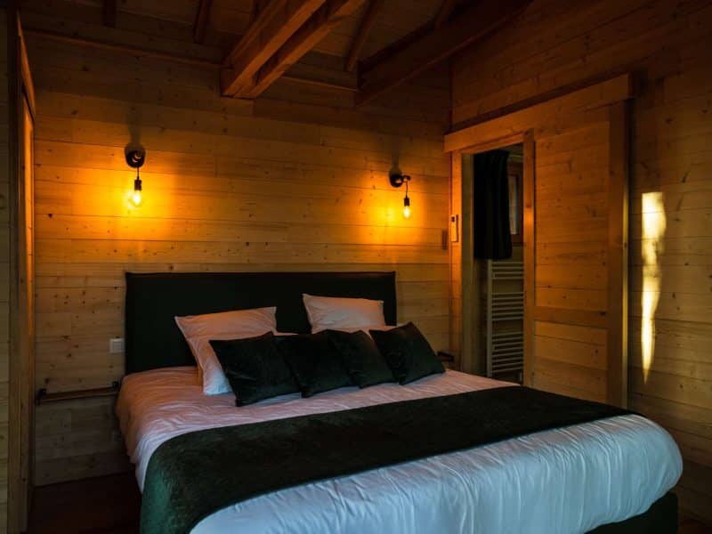 Chalet en bois chaleureux avec un lit confortable et des lumières douces.
