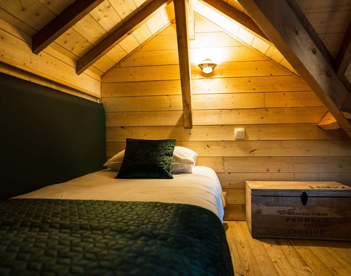 Chalet en bois chaleureux avec lit simple et décoration en bois naturel.