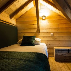 Chalet en bois chaleureux avec lit simple et décoration en bois naturel.
