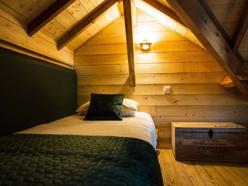 Chalet en bois chaleureux avec un lit simple et des murs en bois naturel.