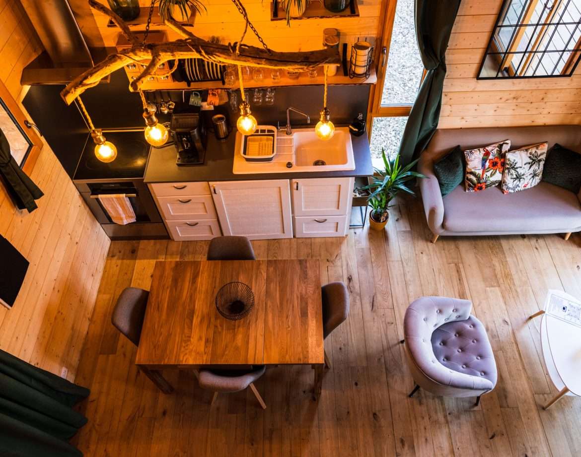 Hébergement insolite en bois avec cuisine moderne et éclairage suspendu chaleureux.