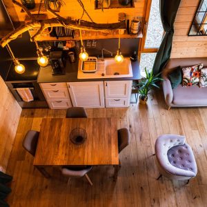 Hébergement insolite en bois avec cuisine moderne et éclairage suspendu chaleureux.