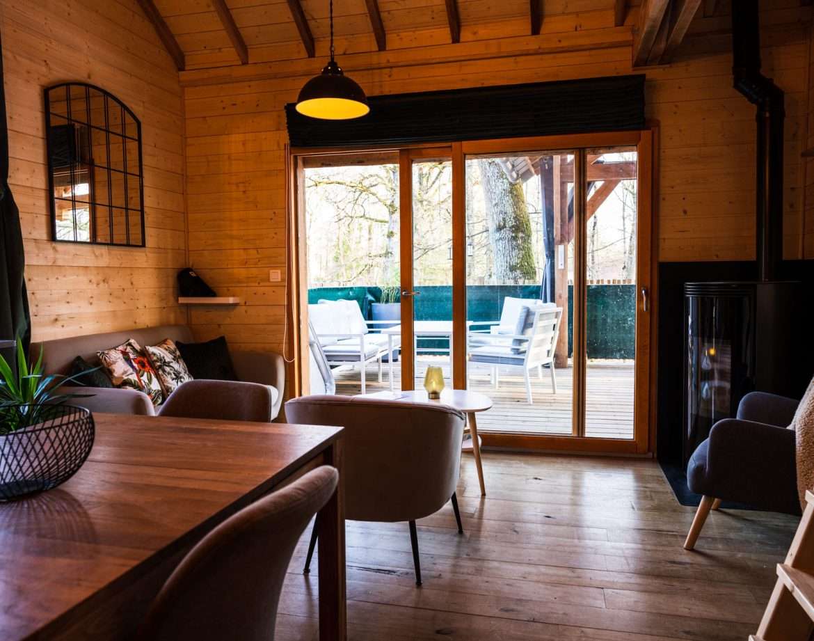 Hébergement insolite en bois avec salon lumineux et terrasse surplombant la nature.