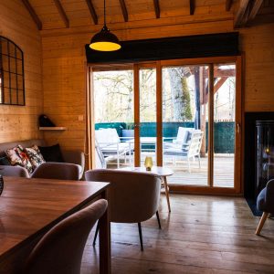 Hébergement insolite en bois avec salon lumineux et terrasse surplombant la nature.