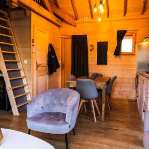 Cabane en bois chaleureuse avec un escalier menant à une mezzanine.