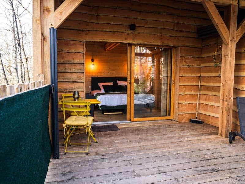 Chalet en bois avec terrasse, offrant une vue sur la nature et un lit confortable.