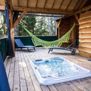 Cabane en bois avec jacuzzi et hamac sur une terrasse en bois. Détente assurée !