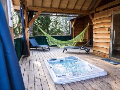 Cabane en bois avec jacuzzi et hamac sur une terrasse en bois. Détente assurée !