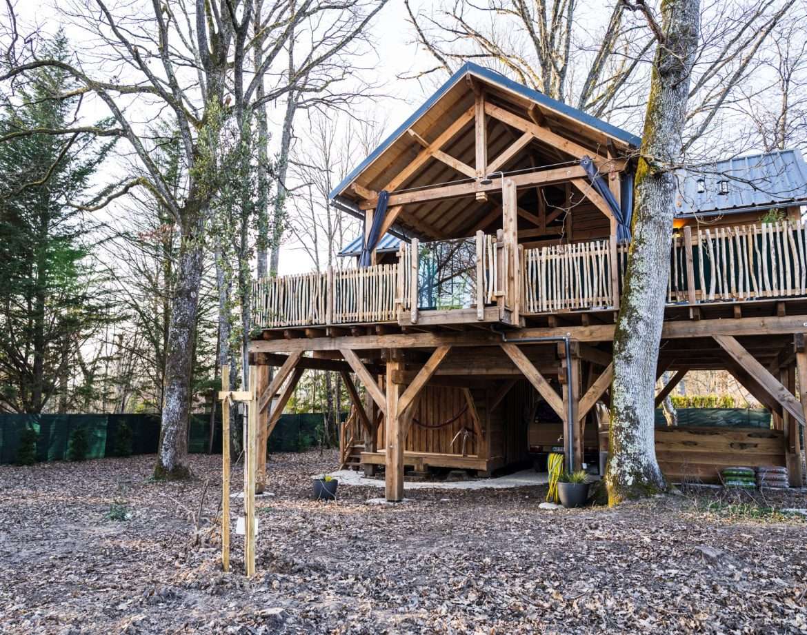 Cabane perchée en bois, entourée darbres, offrant un cadre naturel apaisant.
