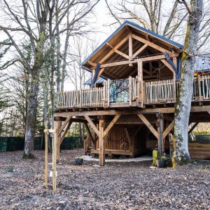 Cabane perchée en bois, entourée darbres, offrant un cadre naturel apaisant.