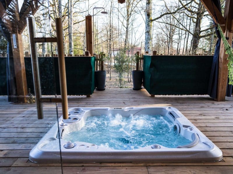 Bungalow avec jacuzzi extérieur, entouré de verdure et de nature apaisante.