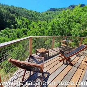 Cabane perchée en Languedoc-Roussillon avec terrasse en bois et vue sur la nature verdoyante.