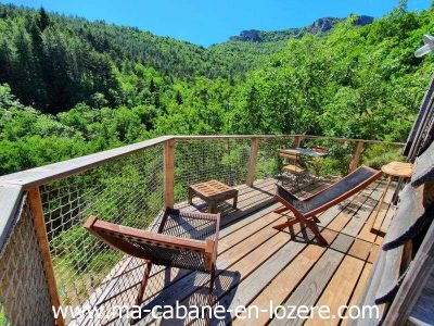 Cabane perchée en Languedoc-Roussillon avec terrasse en bois et vue sur la nature verdoyante.