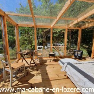 Cabane en bois avec grandes baies vitrées, offrant une vue sur la nature environnante.