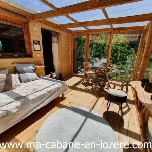 Cabane en bois lumineuse avec grandes baies vitrées et vue sur la nature.