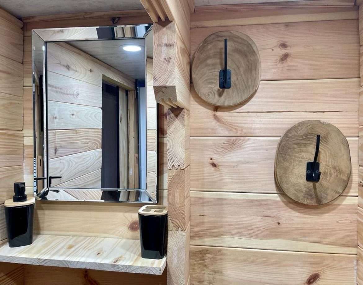 Hébergement insolite en bois à Midi-Pyrénées, avec miroir moderne et décor naturel.